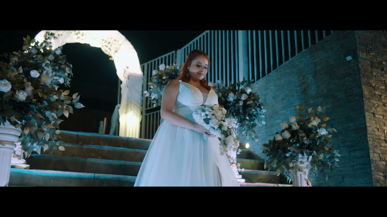 Video cinematográfico de boda: la novia con su ramo junto al arco floral